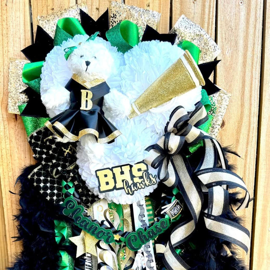 Decorative homecoming mum with ribbons, feathers, and a teddy bear on a wooden background