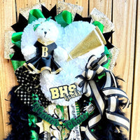 Decorative homecoming mum with ribbons, feathers, and a teddy bear on a wooden background
